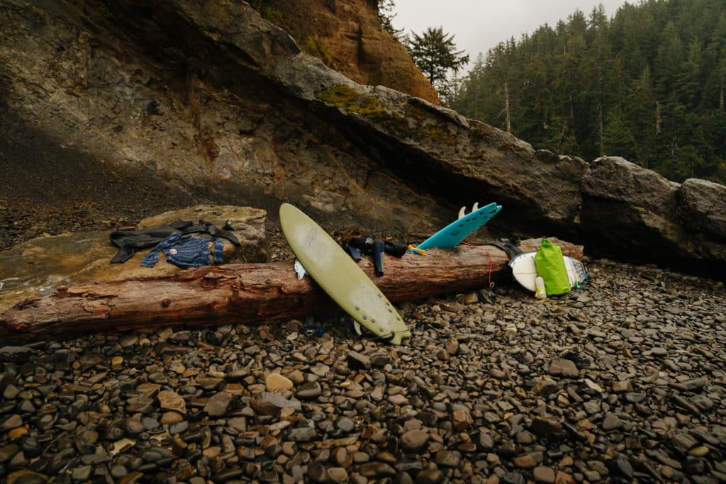 A surfboard is leaning on driftwood on the beach at Oswald West State Park.