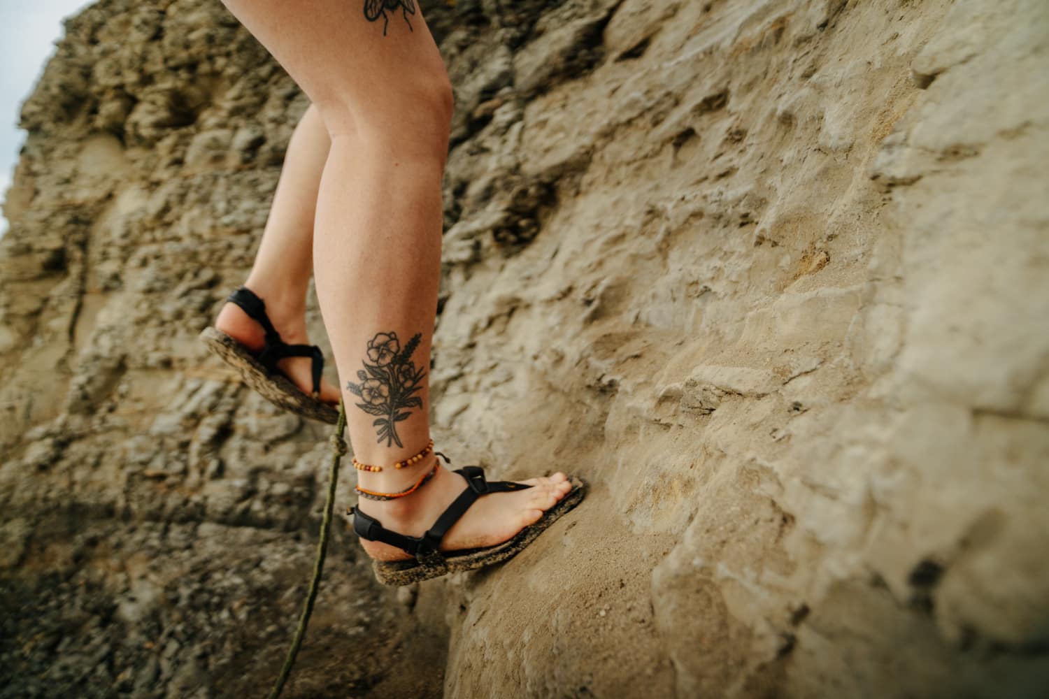 A closeup of sandals on a girl's feet as she climbs down to the beach at Sunset Cliffs Natural Park.