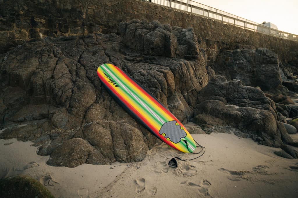A surfboard is resting on a rock at Lover's Point Park.