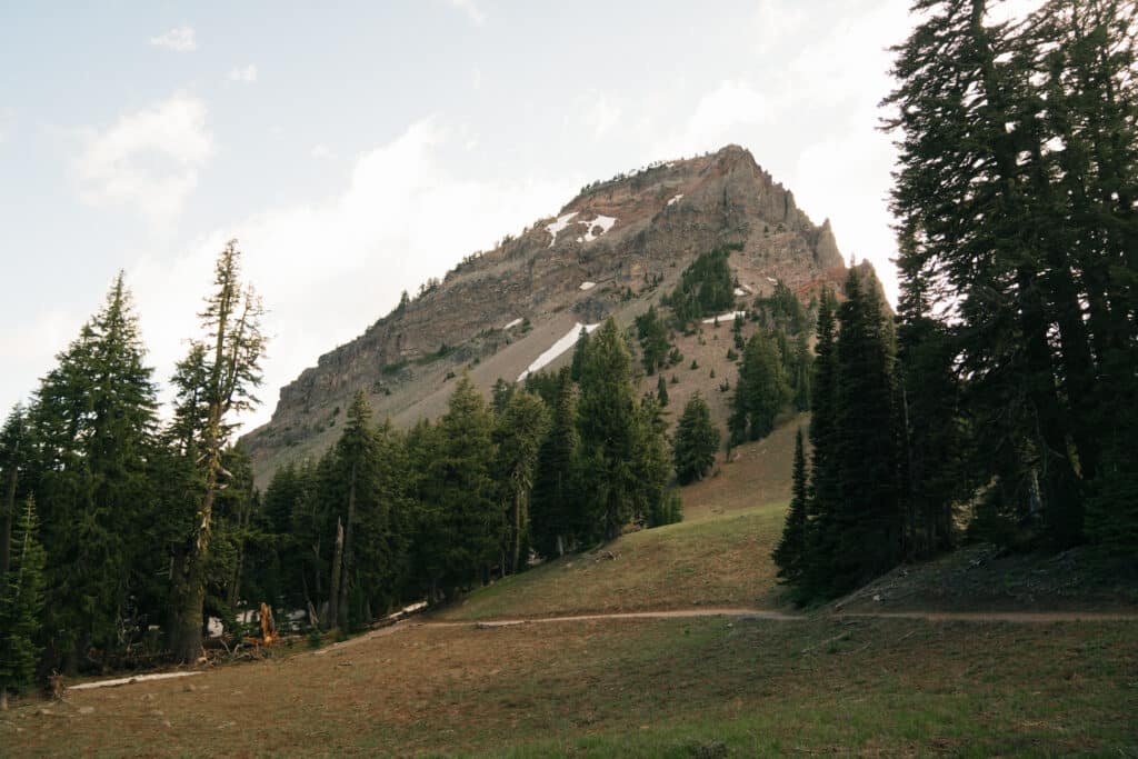 A meadow with a mountain behind it along the trail for one of the best hikes in Crater Lake National Park.