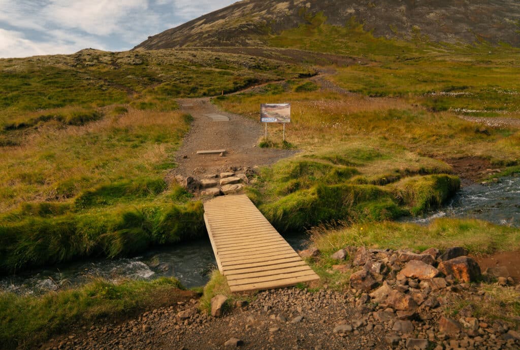 A bridge over the water along the Reykjadalur Hot Spring Thermal River trail.