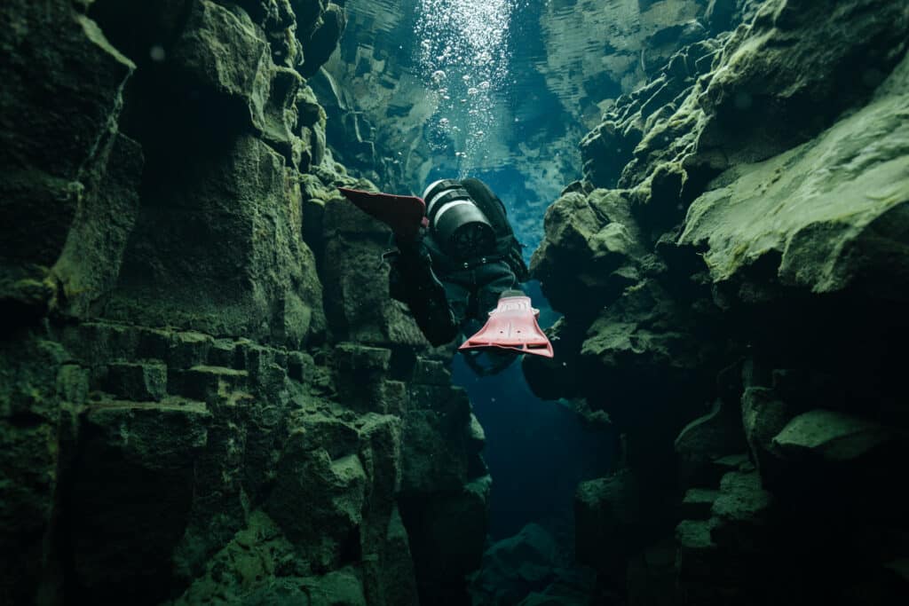 A scuba diver swimming through the Silfra Fissure in Iceland.