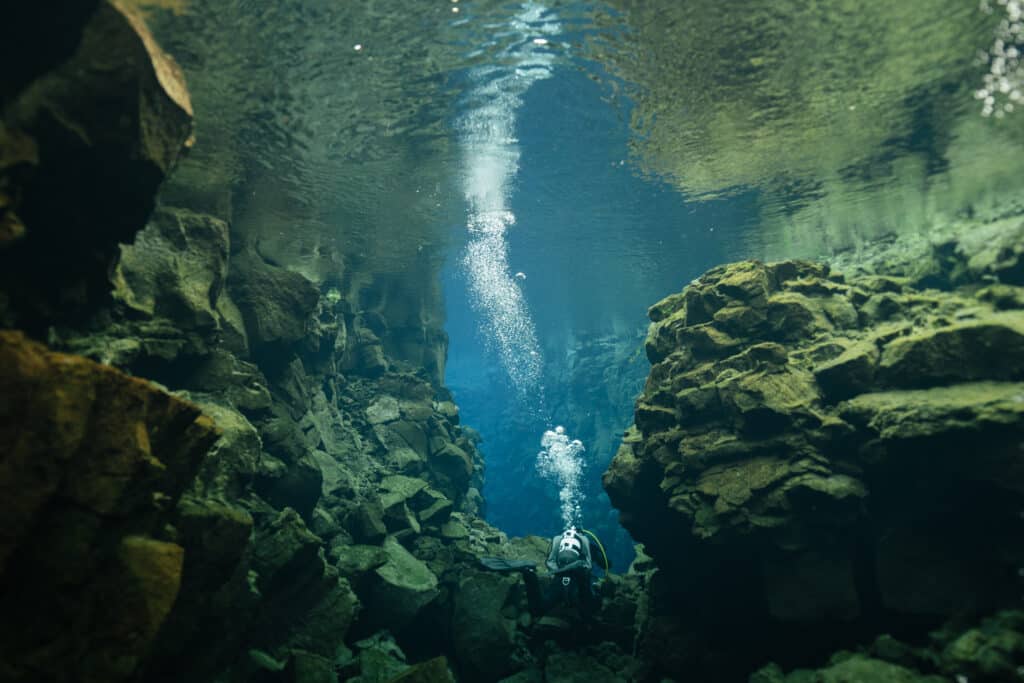 A scuba diver swimming through the Silfra Fissure in Iceland.