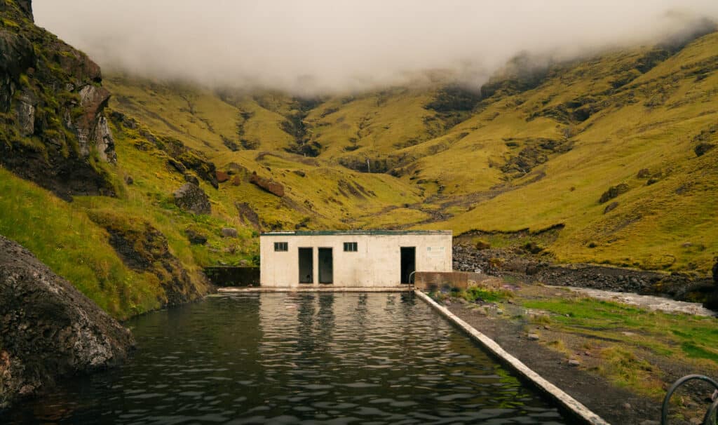 The Seljavallalaug pool, one of the best hot springs in Iceland, with the changing room behind it.
