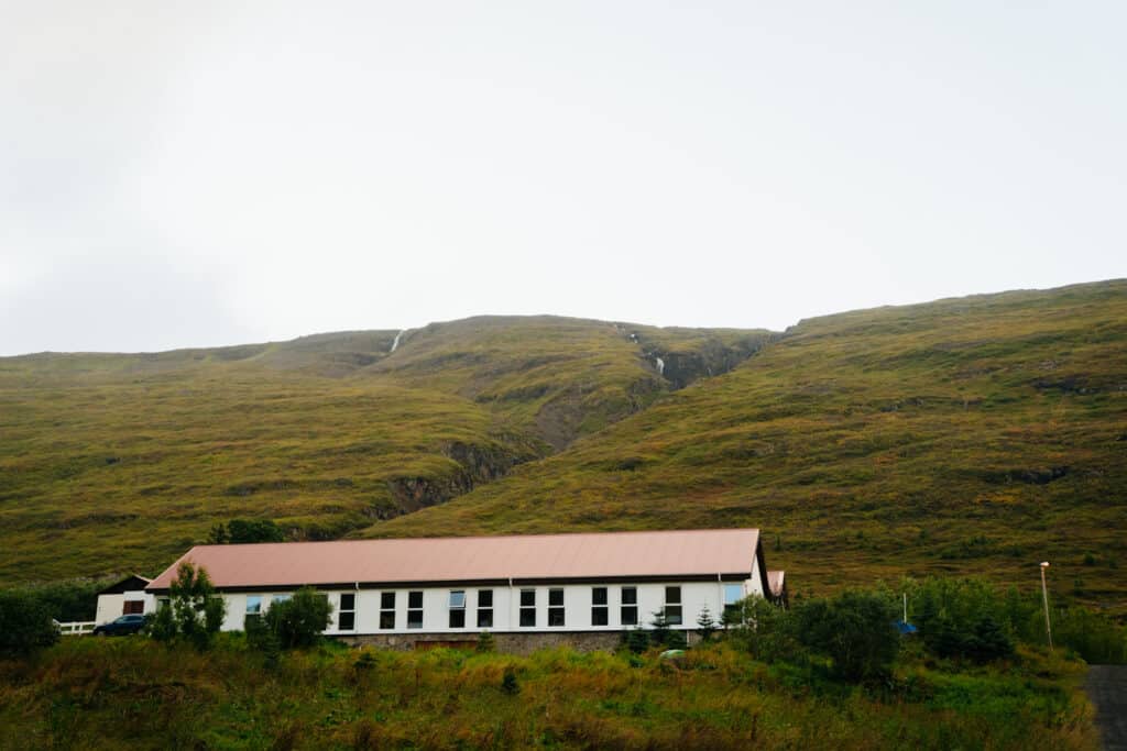 A view of the Country Hotel Heydalur, with mountains behind it.