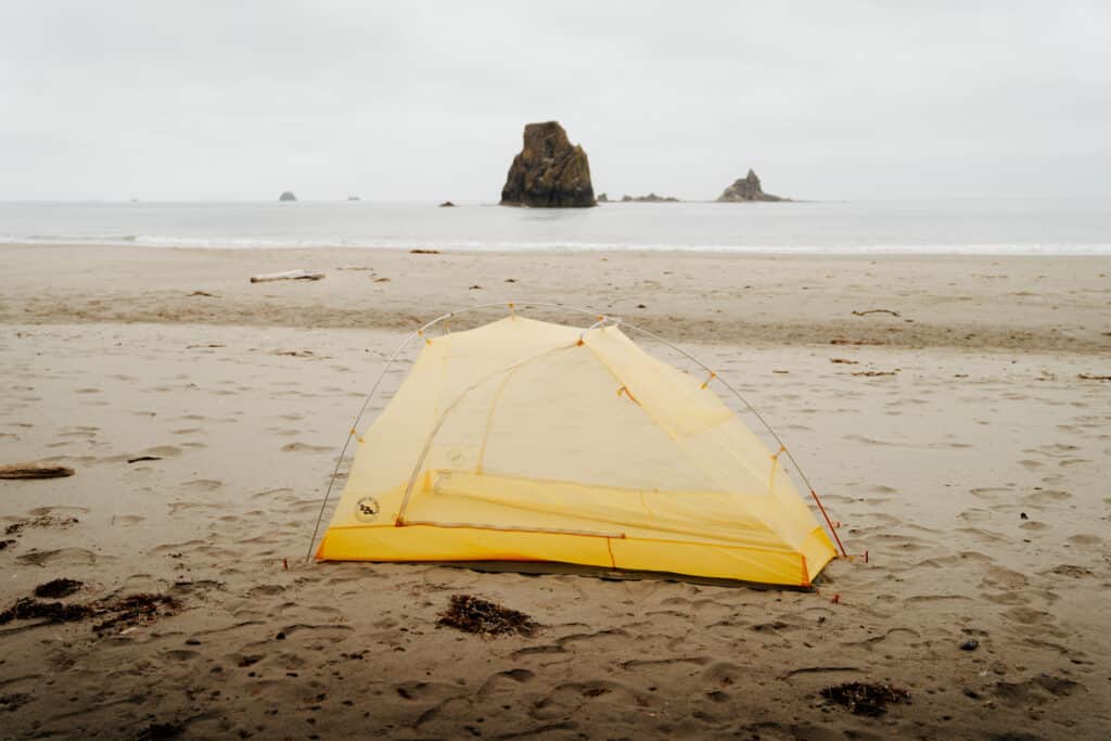 A yellow tent on the beach at a campsite along the South Coast Wilderness trail.